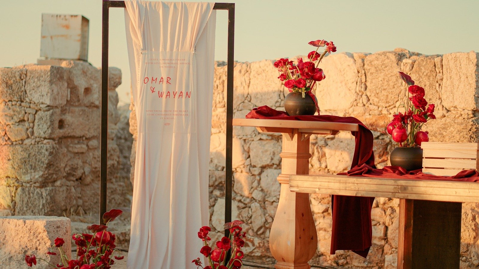 Destination proposal setup with white draped backdrop and red florals at stone venue