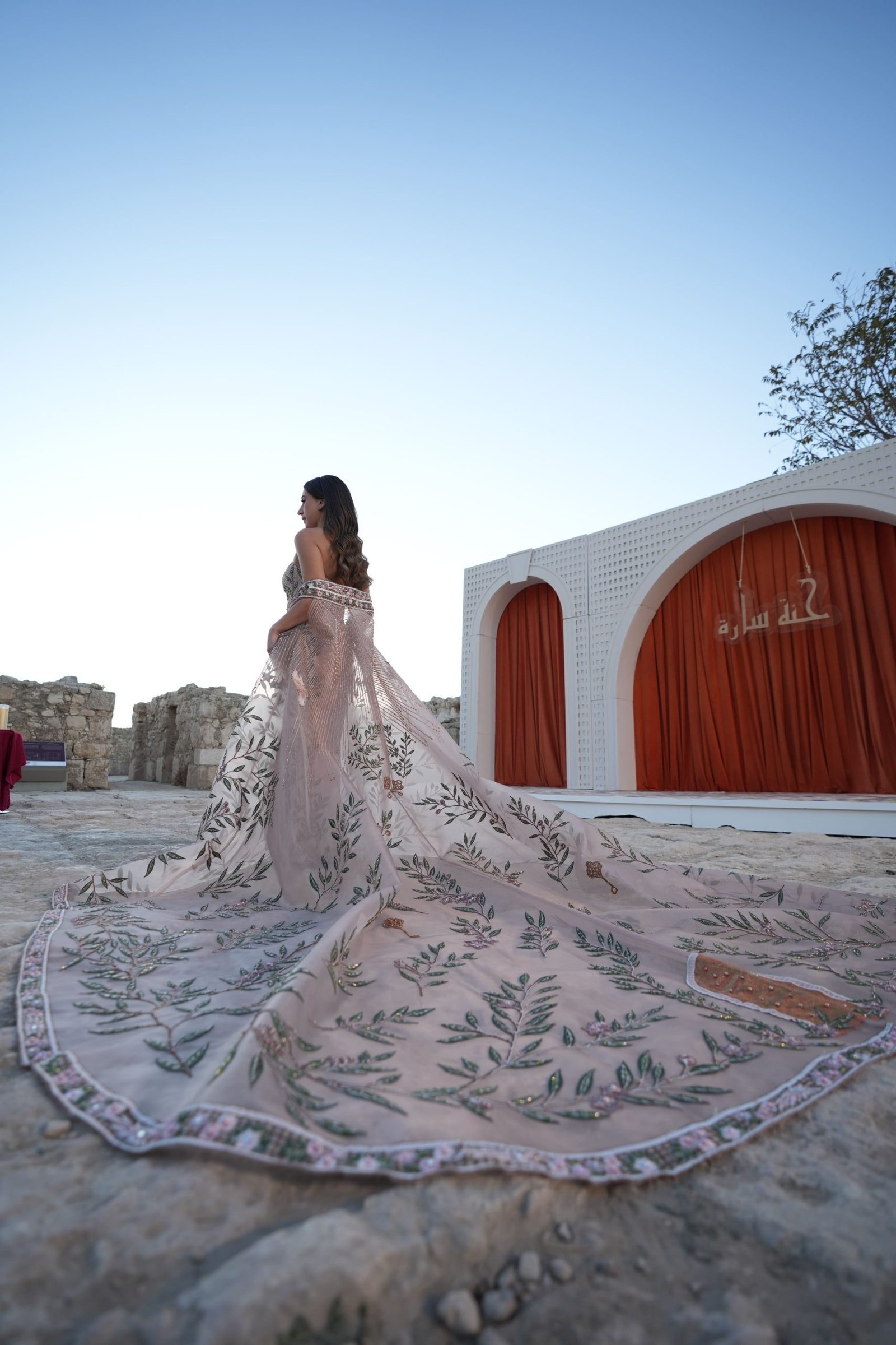 Bride in long train wedding dress posing in front of red wedding stage