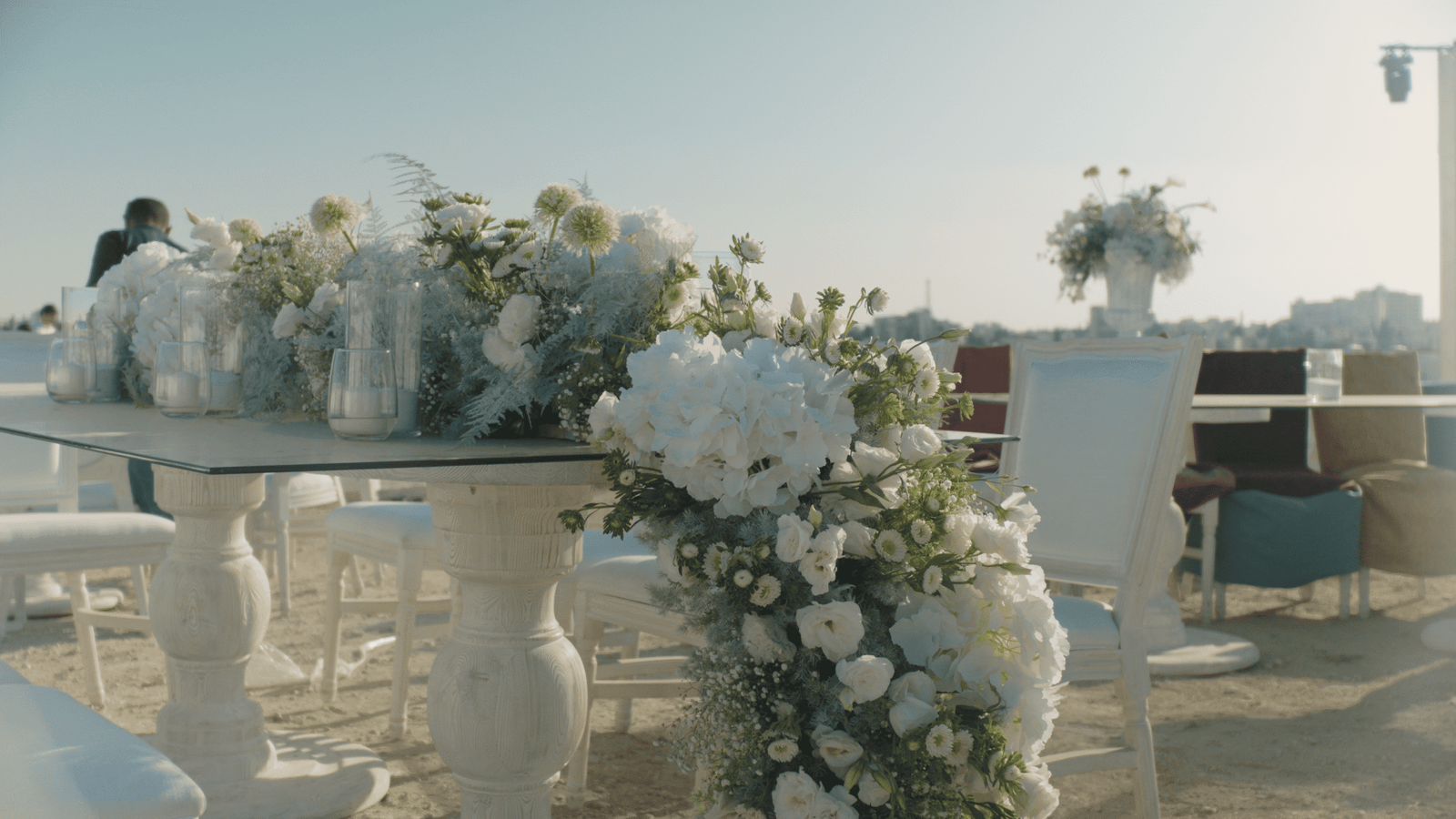 White floral arrangement on pedestal at outdoor waterfront venue