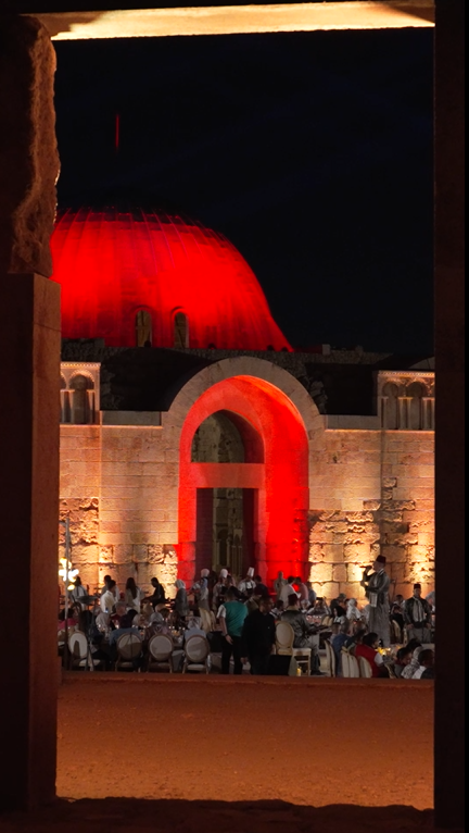 Audience seated in front of Amman Citadel with red architectural lighting